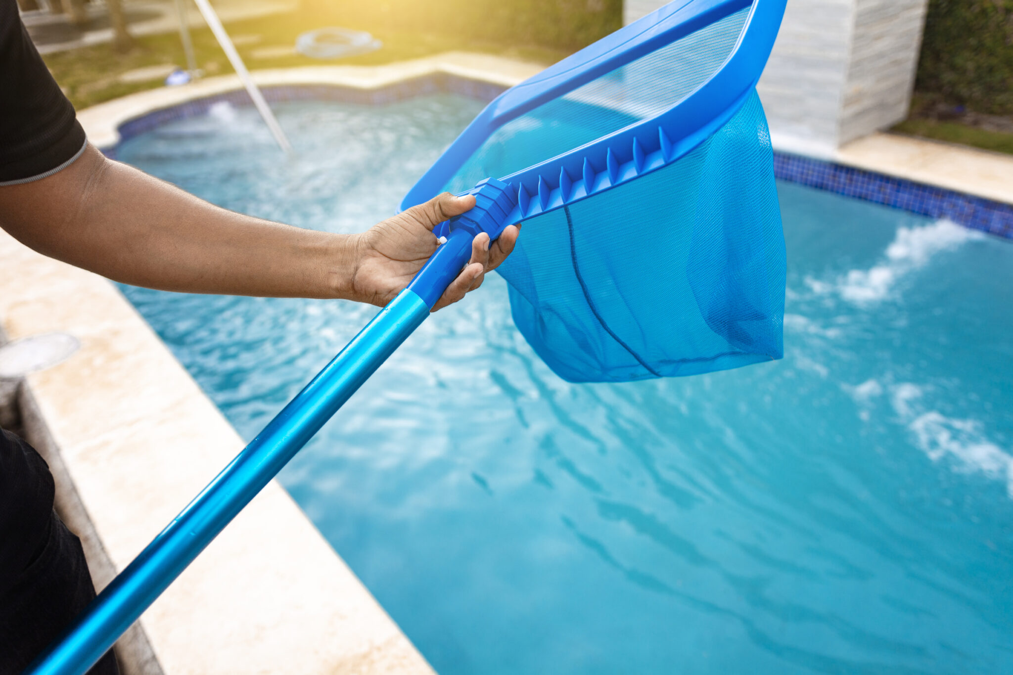 Person with skimmer cleaning pool, Hands holding a skimmer with blue pool in the background. Man cleaning the pool with the Skimmer, A man cleaning pool with leaf skimmer