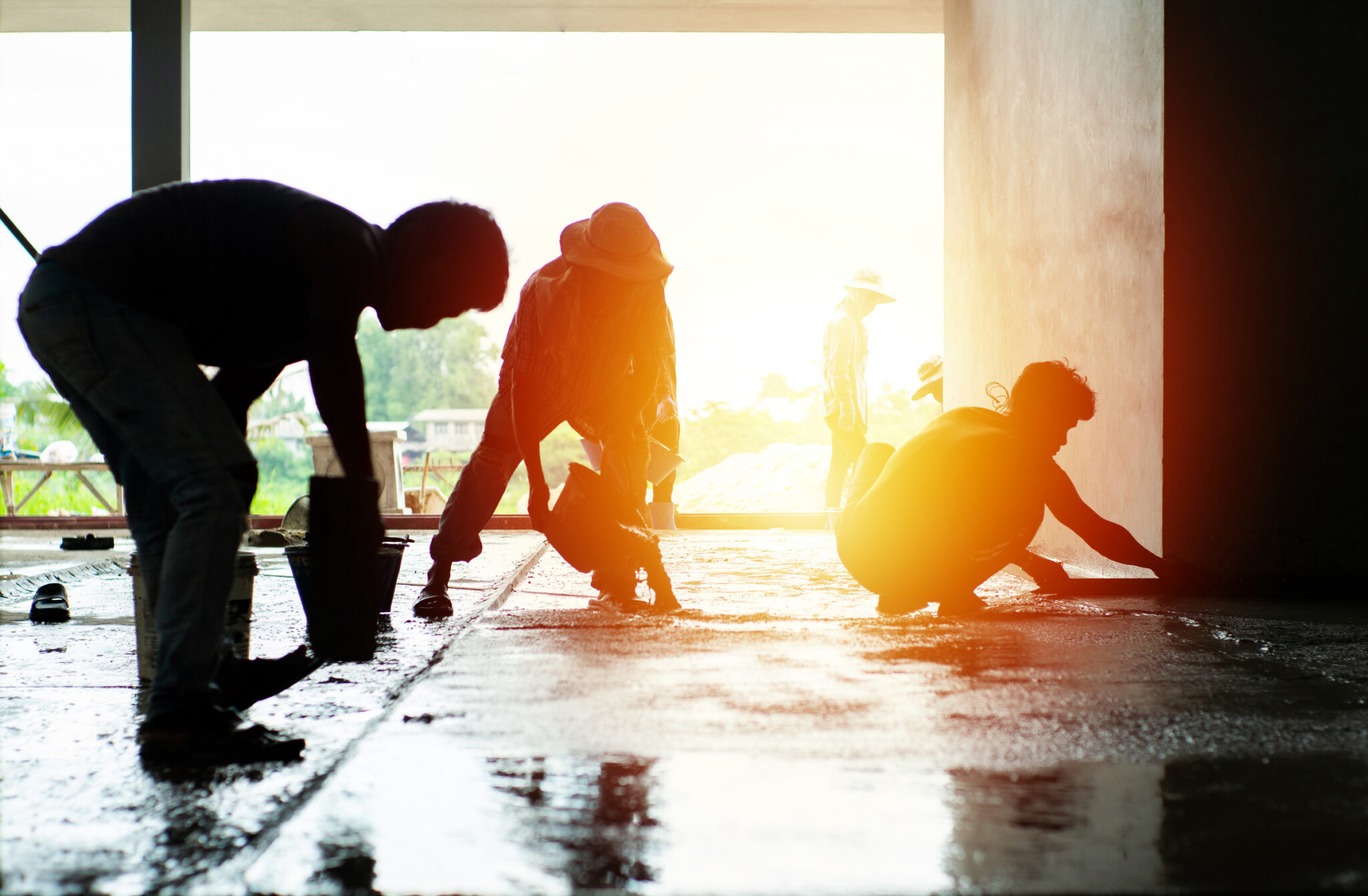 Silhouette group of workers build the cement floor in the house under construction.
